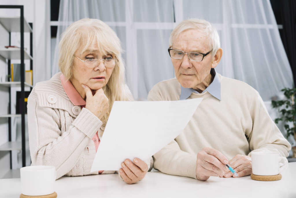 Senior couple reviewing paperwork together at home, possibly seeking legal or financial advice. The scene reflects a thoughtful and collaborative atmosphere.