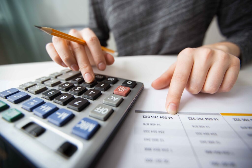 Close-up of hands using a calculator, reviewing financial documents on a desk.